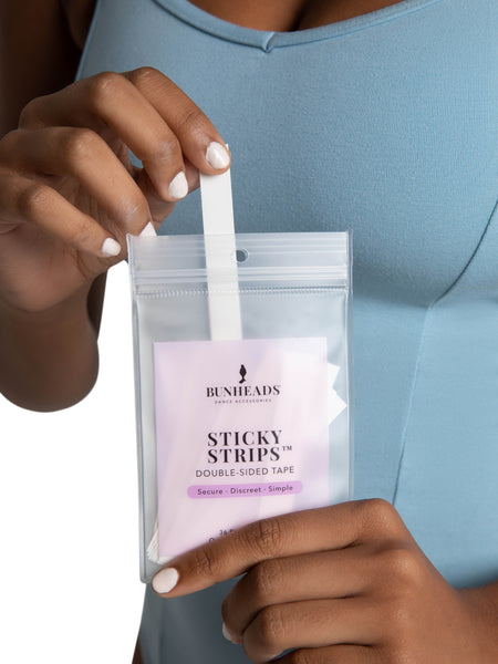 Person holding a package of Bunheads Sticky Strips with a clear background