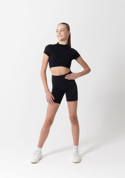 Person wearing a black crop top and black high-waisted shorts on a white background