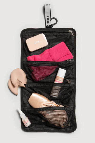Black travel organizer with pink socks, beige shoes, and other items on a light gray background