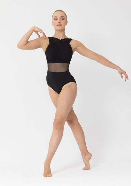 A female model wearing a black gathered mesh leotard with a mesh waist panel, posing with one hand extended gracefully.