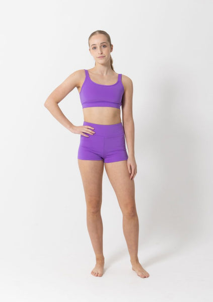 Person wearing a purple sports bra and shorts on a white background