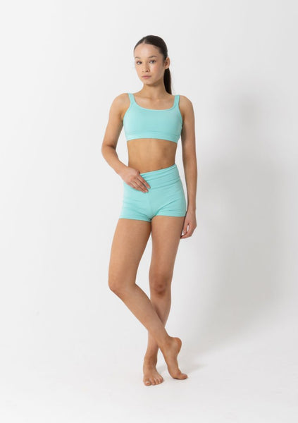 Woman wearing a matching turquoise sports bra and shorts set on a white background
