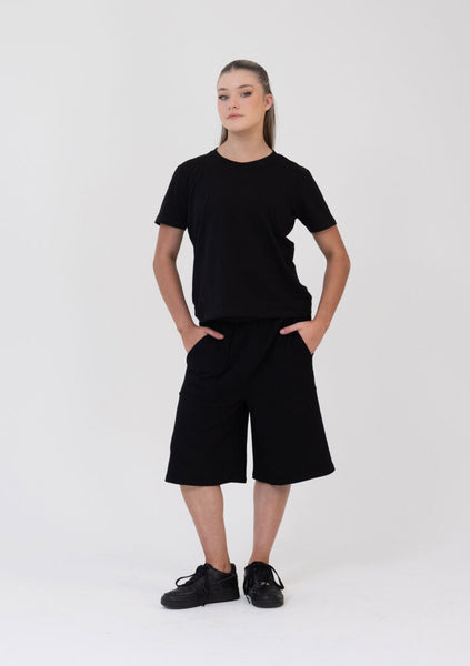 Person wearing a black t-shirt and black shorts on a white background