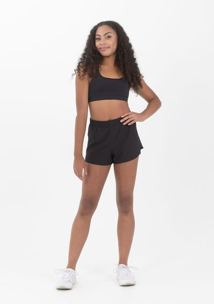 A person wearing a black crop top, black shorts and white sneakers