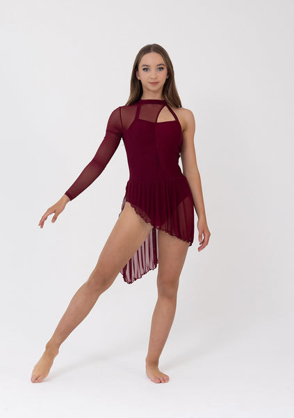 A young female dancer modeling a burgundy long-sleeve skating leotard with sheer mesh panels and a ruffled asymmetrical hem against a plain white studio background.