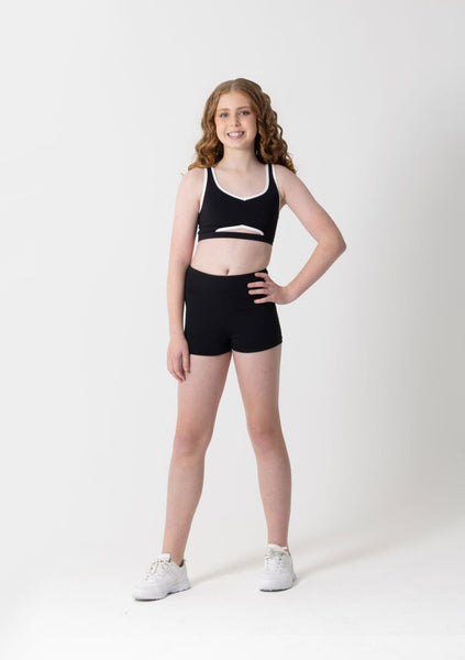 Young girl wearing a black sports bra and shorts set on a white background