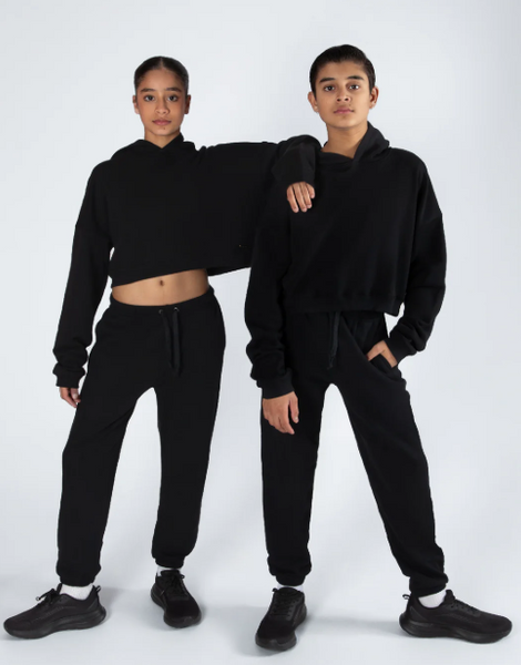 Two people wearing matching black outfits on a white background