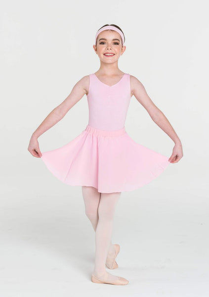 A young girl wearing a pink ballet skirt with an elasticated waistband and a full circle chiffon skirt, posing on one leg.