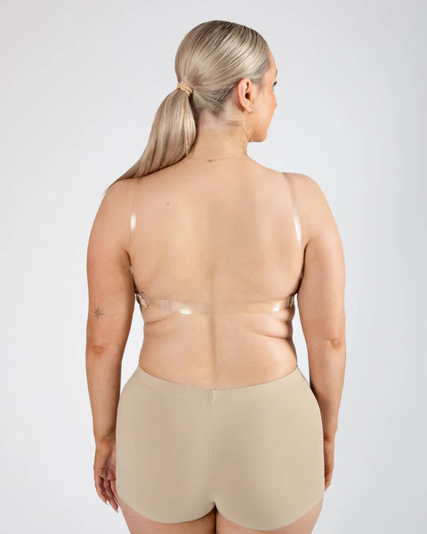 Woman wearing a beige clear back bra and shorts set on a plain background