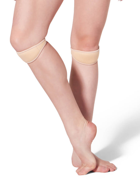 Beige mini knee pad with elastic worn by a person on a light gray background