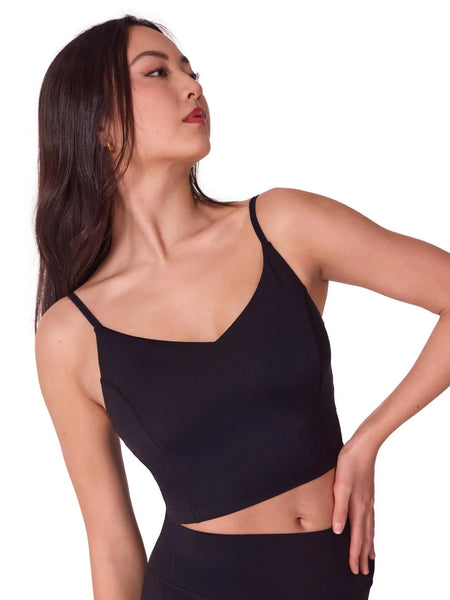 Person wearing a black thin strap sports top on a white background