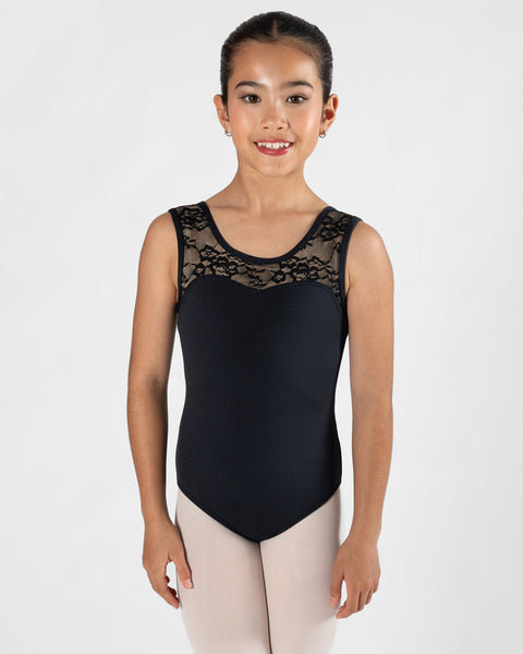 A young girl wearing a black sleeveless dance leotard with black lace detailing across the chest, paired with light pink tights, standing against a plain light gray background.