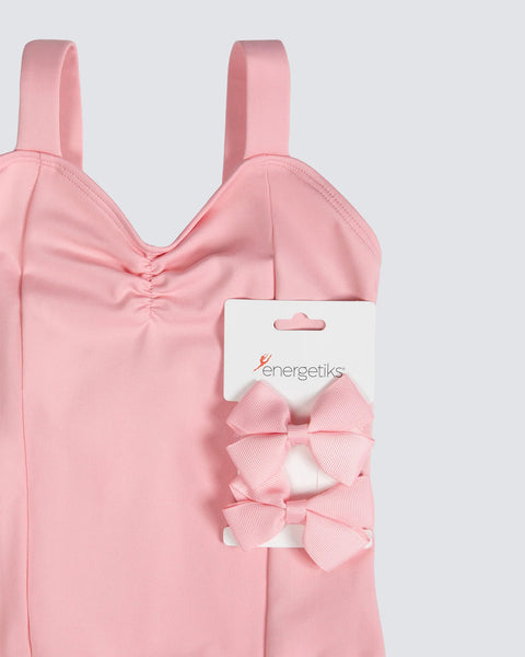 Pink leotard and matching hair tie bows on a light gray background
