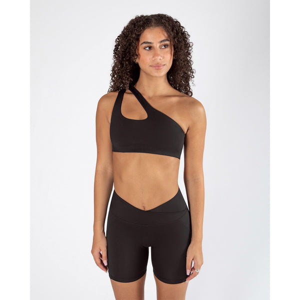 Woman wearing a black sports bra and shorts on a white background
