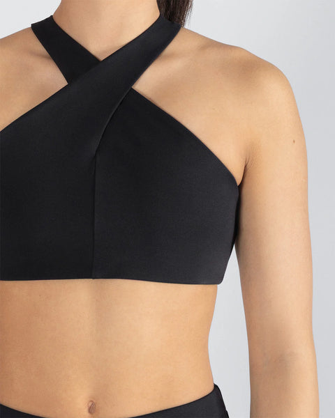 Black sports bra with halter neck, criss-cross design on a neutral background | Dancewear Nation Australia