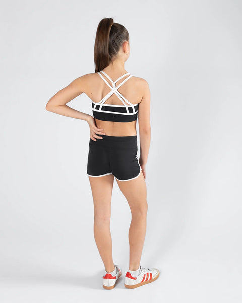 Person wearing a black and white crop top and shorts sports set on a light gray background