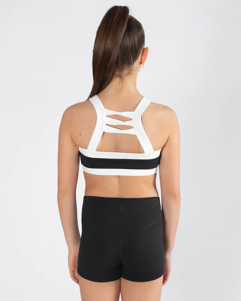 Woman wearing a white sports bra with cut-out design and black shorts on a white background