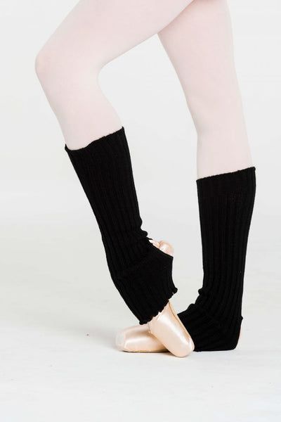 A person wearing black anklewarmers with reinforced stirrup, posed on their toes in a ballet position.