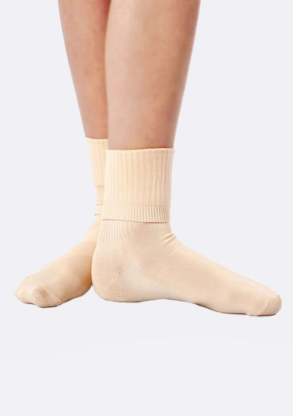 A pair of beige ballet socks on a person's feet, showcasing the ribbed fold-down design.