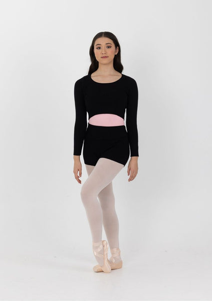 A female model wearing a black ribbed warm up top with a pink band, white leotard, and pink ballet shoes.